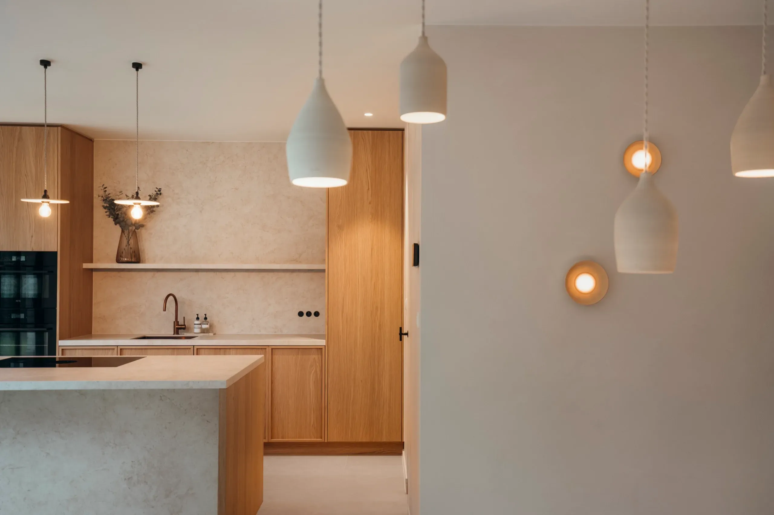 Keuken met eiken kasten, natuurstenen eiland en witte hanglampen