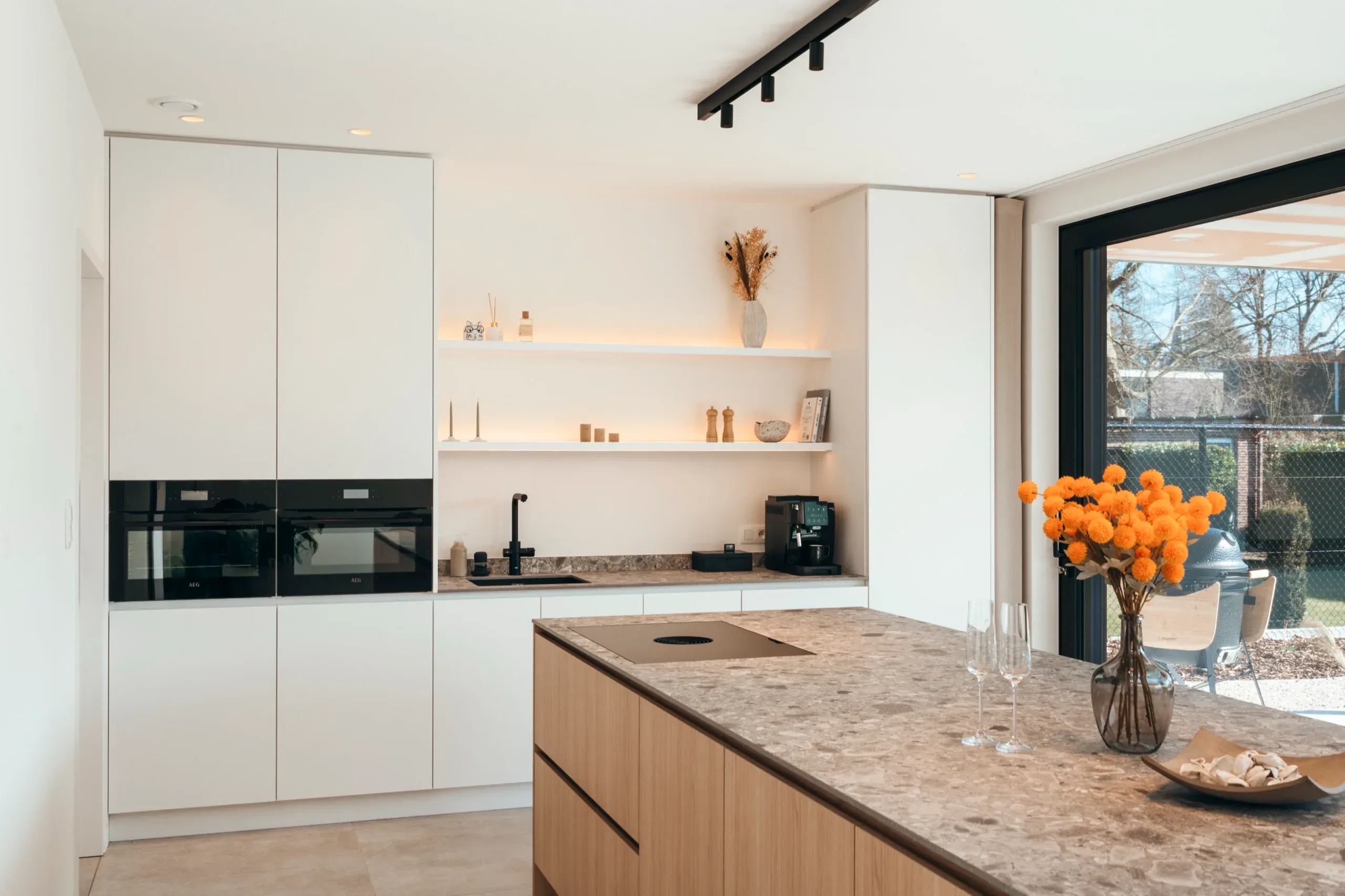 Kookeiland met natuursteenlook en open nissen met verlichting tegen de achterwand